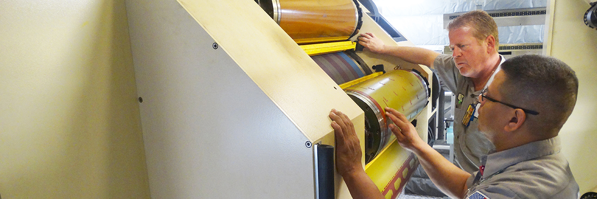 Two men getting trained on operating offset printing machine