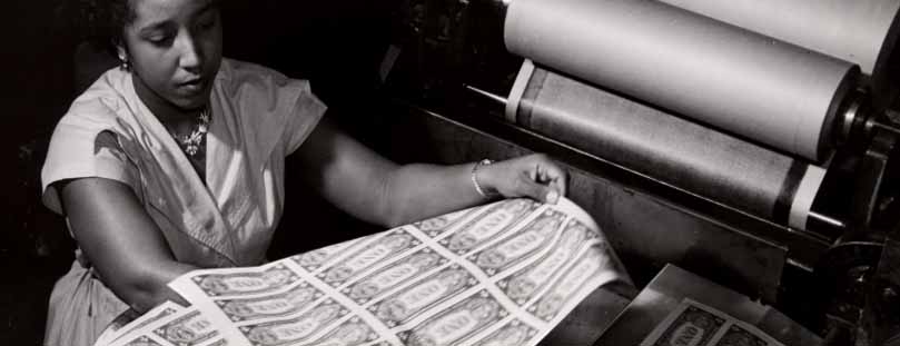 Black and White photo of woman looking at currency sheet