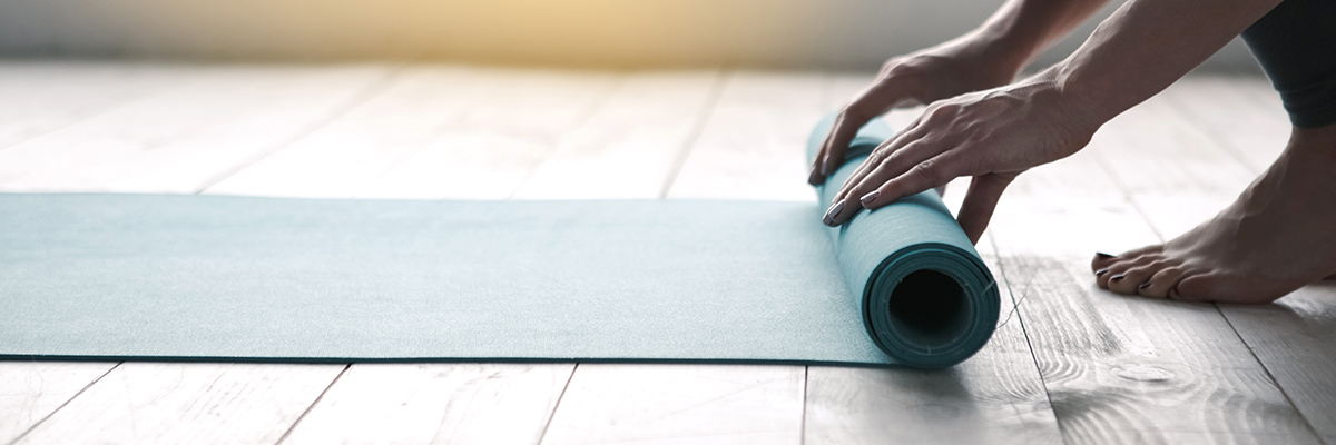Hands unrolling a yoga mat on the floor