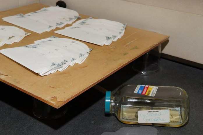 A $100 note is immersed in a bottle of unleaded gasoline for a soak test in the Quality Assurance Lab.