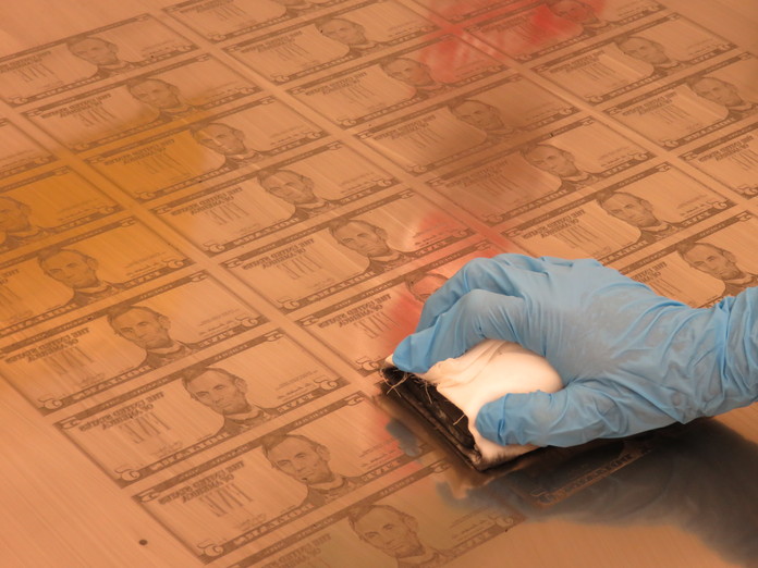 A plate maker prepares a $5 face plate for chrome plating.