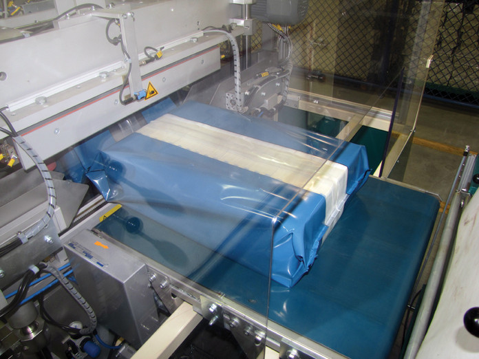 A cash-pack rolls out from the Large Examining Printing Equipment’s seal bar prior to entry into the shrink tunnel.